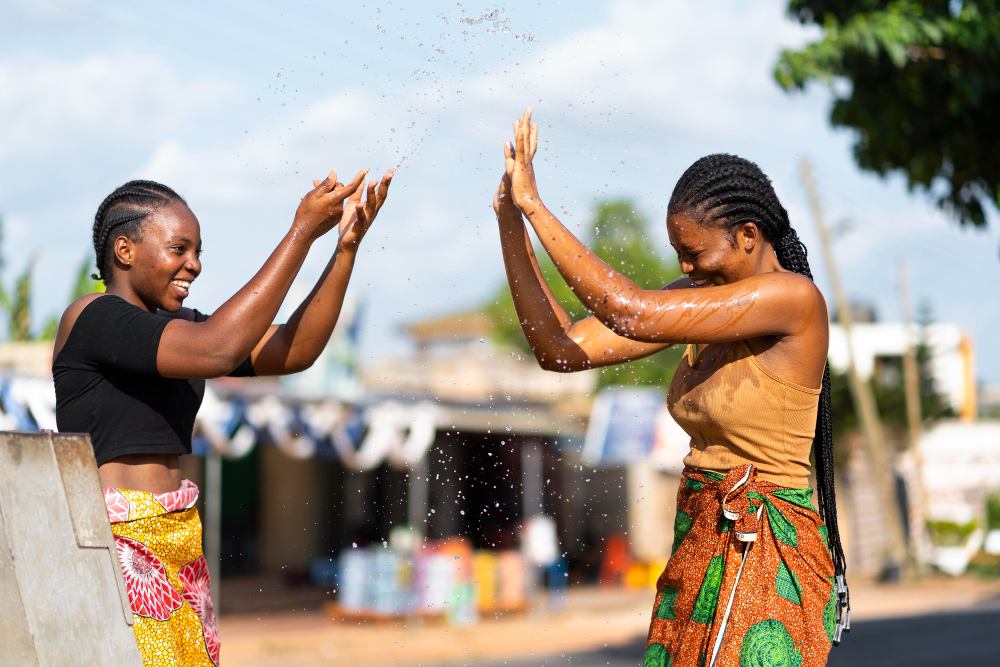A pair of black women having fun splashing water at each other